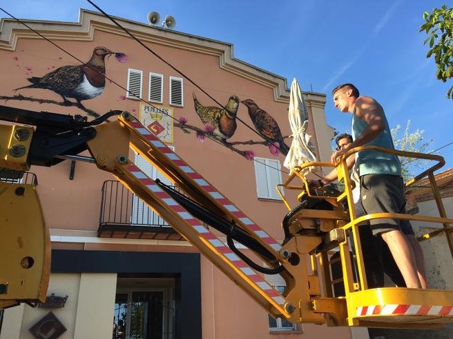 El artista callejero Slim Art observa su obra encima de una grúa.